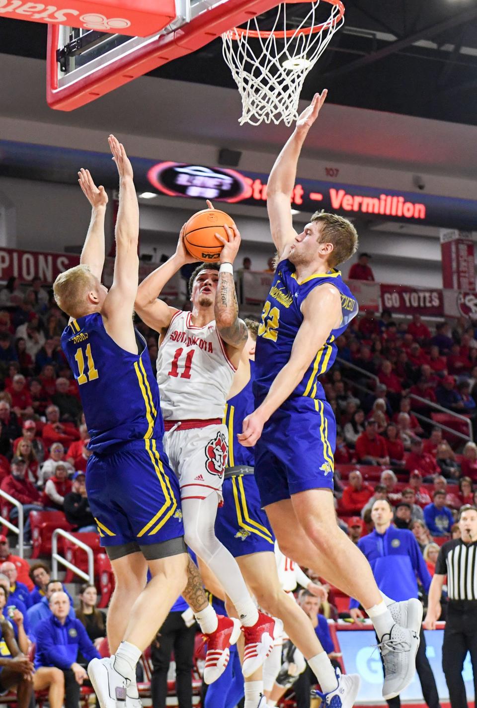 South Dakota’s Mason Archambault is overwhelmed under the basket by South Dakota State’s Matthew Mors and Matt Dentlinger in a rivalry matchup on Saturday, January 14, 2023, at the Sanford Coyote Sports Center in Vermillion.