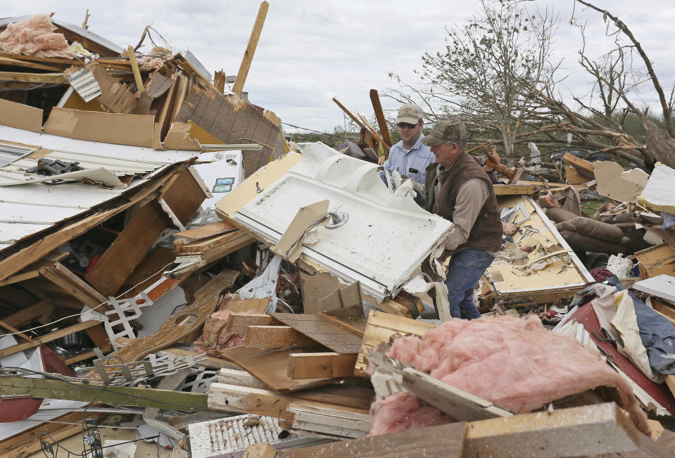 Roman Brown, left and Sam Crawford, right move part of a shower wall out of their way as they help a friend look for their medicine in their destroyed home Sunday, April 14, 2019, along Seely Drive outside of Hamilton, Miss. after an apparent tornado touched down Saturday, April, 13, 2019. (AP Photo/Jim Lytle)