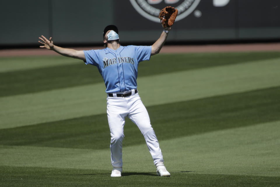 Seattle Mariners' third baseman Patrick Wisdom wears a mask as he waves off other players to make a catch, Friday, July 10, 2020, during a "summer camp" baseball scrimmage game in Seattle. (AP Photo/Ted S. Warren)