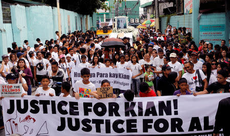 Mourners display a streamer during a funeral march for Kian delos Santos, a 17-year-old student who was shot during anti-drug operations in Caloocan, Metro Manila, Philippines August 26, 2017. REUTERS/Erik De Castro