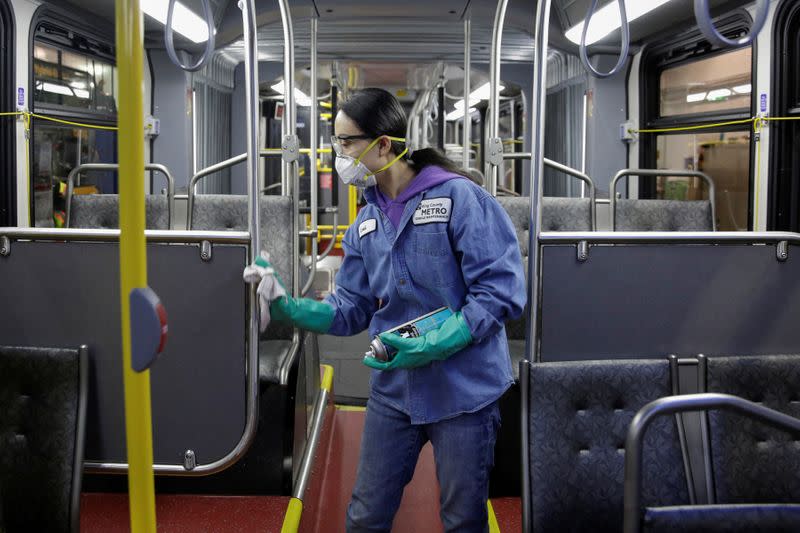 FILE PHOTO: Vehicle Maintenance Utility Service Worker Thiphavanh 'Loui' Thepvongsa wipes down an off-duty bus with a disinfectant during a routine cleaning at the King County Metro Atlantic and Central Base in Seattle