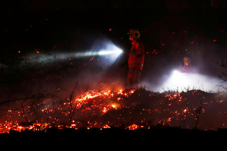 Firefighters tackle a fire on a patch of moorland above the village of Uppermill, Britain, April 22, 2019. REUTERS/Phil Noble