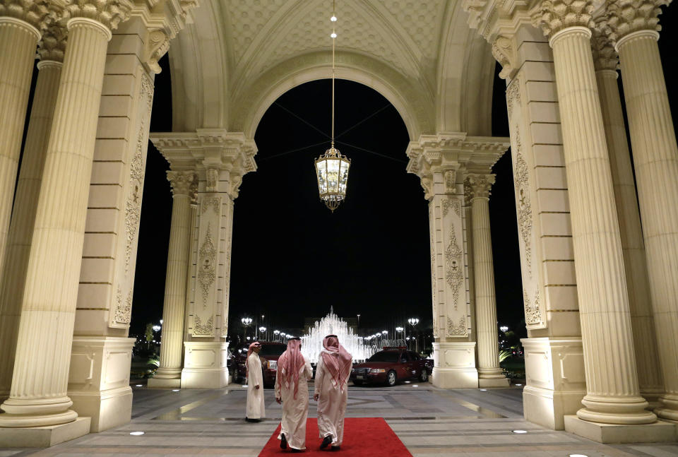 Saudi men walk at the entrance to the Ritz-Carlton Hotel.