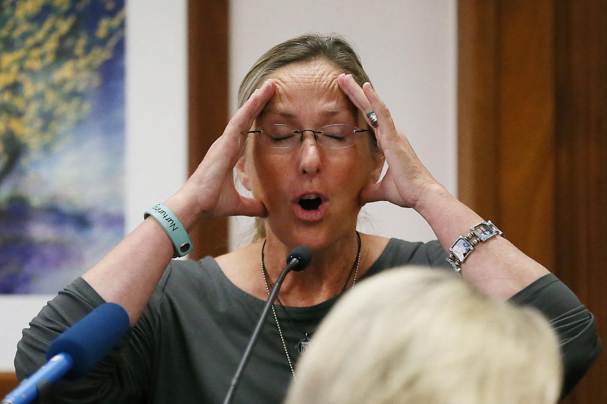 Scarlett Lewis holds her hands up to her face while on the witness stand.