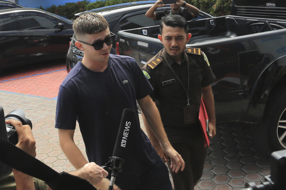 Bodhi Mani Risby-Jones from Queensland, Australia, left, is escorted by a prosecutor upon arrival at the local immigration office in Meulaboh, Aceh, Indonesia on Wednesday, June 7, 2023. The Australian surfer who was jailed for attacking several people while drunk and naked in Indonesia's deeply conservative Muslim province of Aceh will be deported back to his country after he agreed to apologize and pay compensation, officials said Wednesday. (AP Photo/Sultan Ikbal Abiyyu)