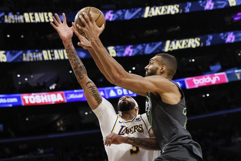 Minnesota Timberwolves center Rudy Gobert, right, scores against Los Angeles Lakers forward-center Anthony Davis during the first half of an NBA basketball game, Sunday, April 7, 2024, in Los Angeles. (AP Photo/Etienne Laurent)