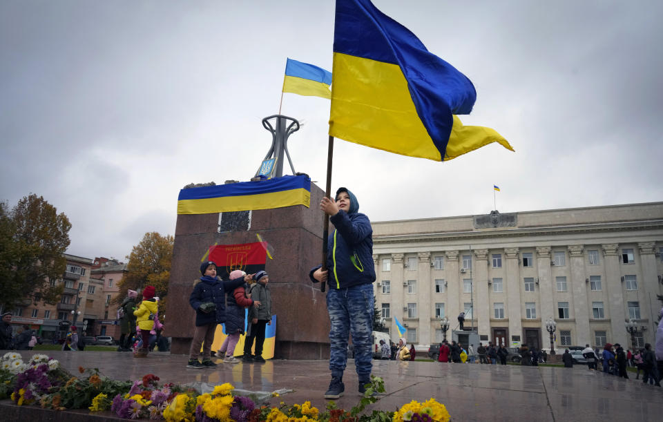 A boy holds a Ukrainian flag in central Kherson, Ukraine, Sunday, Nov. 13, 2022. The Russian retreat from Kherson marked a triumphant milestone in Ukraine's pushback against Moscow's invasion almost nine months ago. (AP Photo/Efrem Lukatsky)