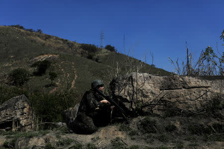 A Brazilian Army soldier takes cover during a shootout with drug gangs during an operation in Alemao slums complex in Rio de Janeiro, Brazil August 20, 2018. REUTERS/Ricardo Moraes