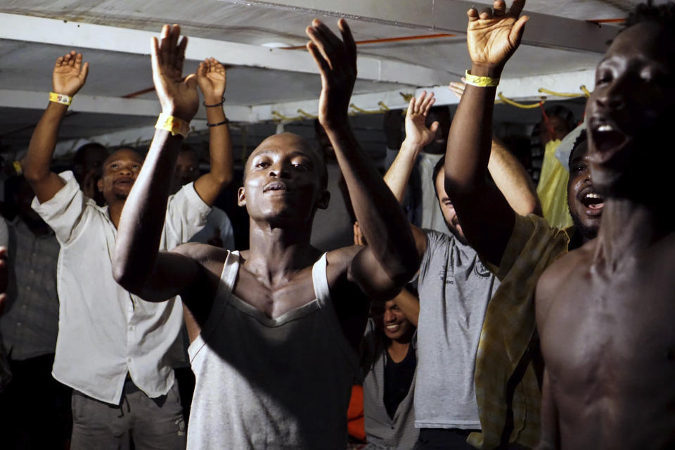 Migrants onboard the Open Arms vessel celebrate the news of an Italian prosecutor who has ordered that the migrants be disembarked on the island of Lampedusa, southern Italy, Tuesday, Aug. 20, 2019. At least 15 more migrants jumped into the sea Tuesday from the Open Arms rescue ship in desperate bids to reach the shores of Italy after 19 days of being on the boat in deteriorating conditions as Italy refuses to open its ports. (AP Photo/Francisco Gentico)