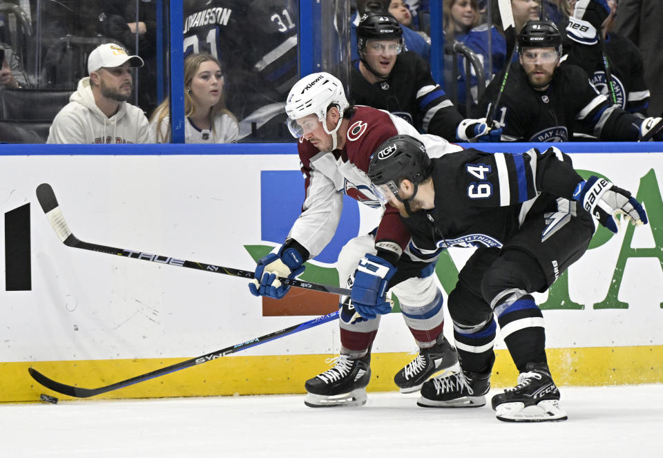 Colorado Avalanche center Ryan Johansen (12) and Tampa Bay Lightning center Tyler Motte (64) vie for the puck during the first period of an NHL hockey game Thursday, Feb. 15, 2024, in Tampa, Fla. (AP Photo/Jason Behnken)