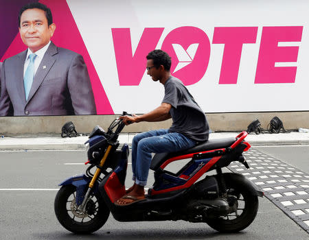 A man rides a motorcycle past an image of Maldives President Abdulla Yameen on a road ahead of the presidential election in Male, Maldives September 19, 2018. REUTERS/Ashwa Faheem