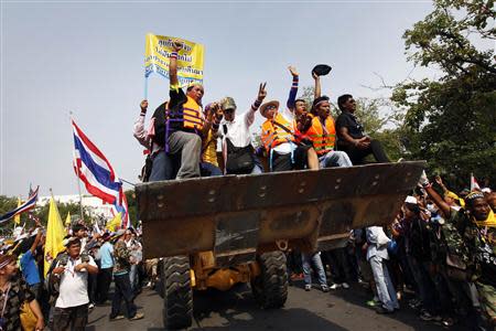 Anti-government protesters celebrate on a front loader used to knock down a concrete barricade outside the Government House in Bangkok December 9, 2013. Thai Prime Minister Yingluck Shinawatra dissolved parliament on Monday and called a snap election, but anti-government protest leaders pressed ahead with mass demonstrations seeking to install an unelected body to run the country. REUTERS/Kerek Wongsa