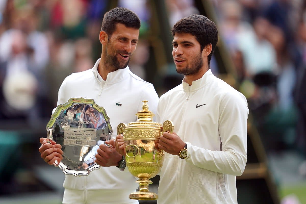 Carlos Alcaraz with the trophy, alongside Novak Djokovic (PA)