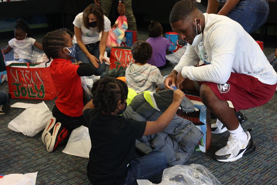 DeCalon Brooks, 22, kneels down and helps a Pineview Elementary student with his new winter coat.