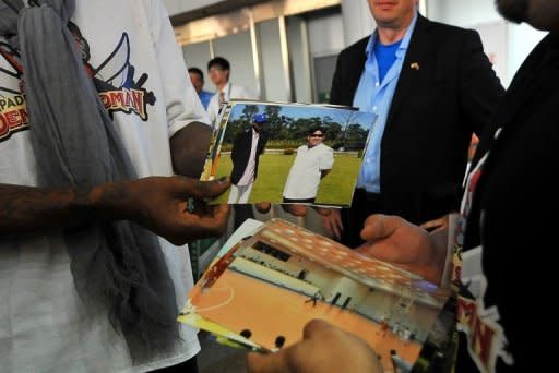 Dennis Rodman shows pictures of him reportedly with North Korea's Kim Jong-Un to the media at the Beijing airport on September 7, 2013. Rodman was reported to have thanked his host for his "expression of good faith towards the Americans" and presented Kim and his wife with a gift