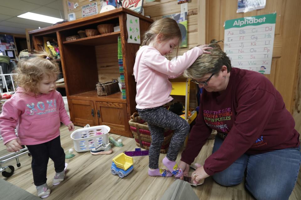 Maebry Davies, left, and Eloise Boycks try on dressy open toe shoes with the help of owner Tuesday, February 28 2023, at Kids Are Us Family Child Care in Oshkosh, Wis.