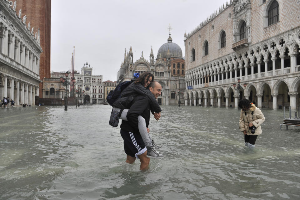 People cross flooded St. Mark's Square in Venice, Italy, Thursday, Nov. 1, 2012. High tides have flooded Venice, leading Venetians and tourists to don high boots and use wooden walkways to cross St. Mark's Square and other areas under water. Flooding is common this time of year and Thursday's level that reached a peak of 55 inches (140 centimeters) was below the 63 inches (160 centimeters) recorded four years ago in the worst flooding in decades. (AP Photo/Luigi Costantini)