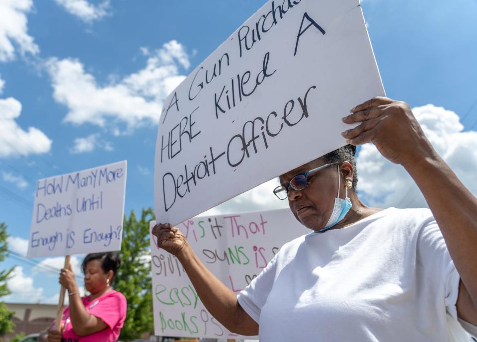 Carol Banks, right, of Detroit, holds a sign during a press conference before a protest outside Action Impact Firearms & Training Center in Eastpointe on July 12, 2022. The gun shop is where the Draco firearm used in the killing of Detroit police officer Loren Courts was purchased.