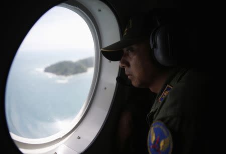 A crew member on an Indonesian Maritime Surveillance looks out the window during a search for AirAsia's Flight QZ8501, north of Bangka island December 30, 2014. REUTERS/Darren Whiteside