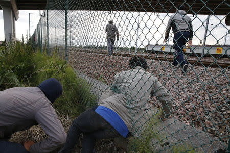 Migrants make their way through a hole ina fence near near train tracks as they attempt to access the Channel Tunnel in Frethun, near Calais, France, July 29, 2015. REUTERS/Pascal Rossignol