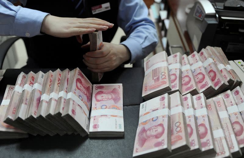 FILE PHOTO: FILE PHOTO: An employee counts 100 Chinese yuan banknotes at a bank in Hefei