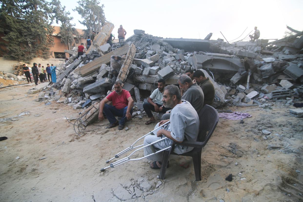 Palestinians sit by the building destroyed in an Israeli airstrike in Rafah, Gaza Strip, Saturday, Oct. 14, 2023. (AP Photo/Hatem Ali) ORG XMIT: DV118