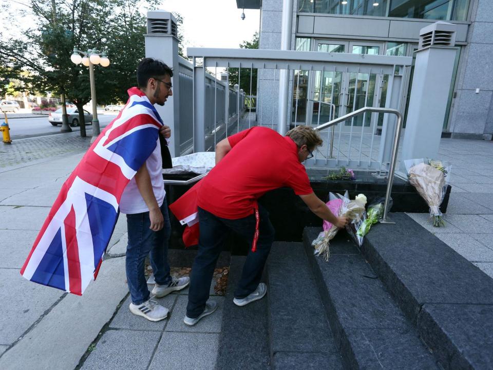 Two men lay flowers at the British High Commission following Queen Elizabeth II's death.