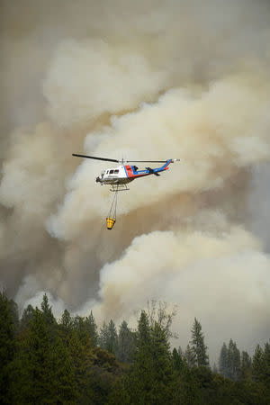 A helicopter carries water while battling the Ponderosa Fire east of Oroville, California, U.S. August 30, 2017. REUTERS/Noah Berger