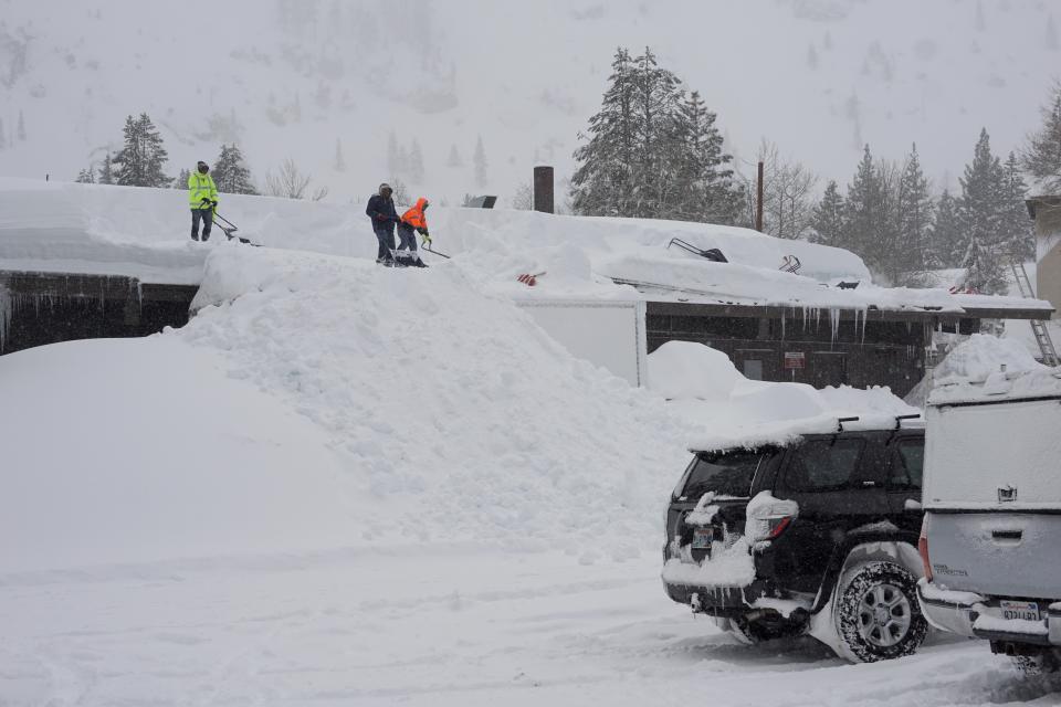 Workers clear snow off the roof of a building during a blizzard Sunday, March 3, 2024, in Olympic Valley, California (AP)