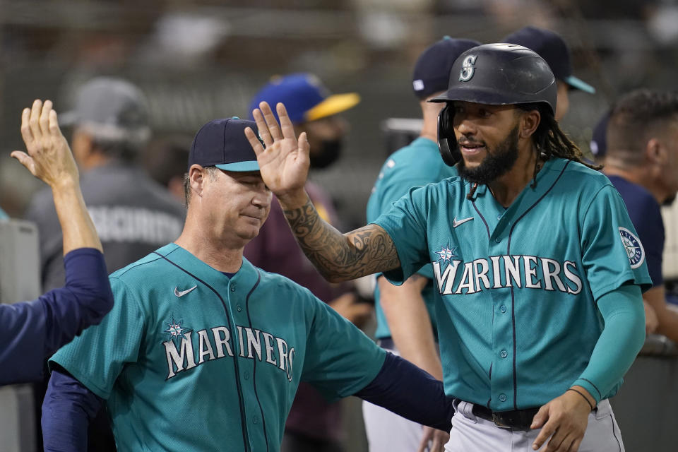 Seattle Mariners' J.P. Crawford, right, is congratulated by manager Scott Servais, left, and teammates after scoring a run against the Oakland Athletics during the third inning of a baseball game in Oakland, Calif., Monday, Sept. 20, 2021. (AP Photo/Jeff Chiu)
