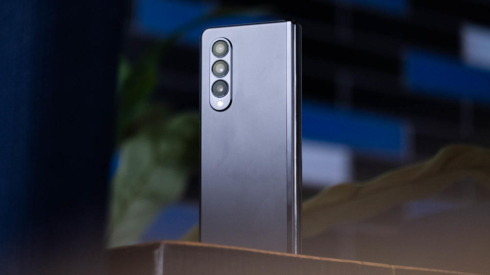 The Samsung Galaxy Z Fold 3 standing on a desk with its triple camera system facing the camera.