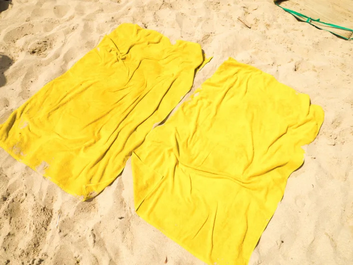 Two yellow beach towels laid out on the sand