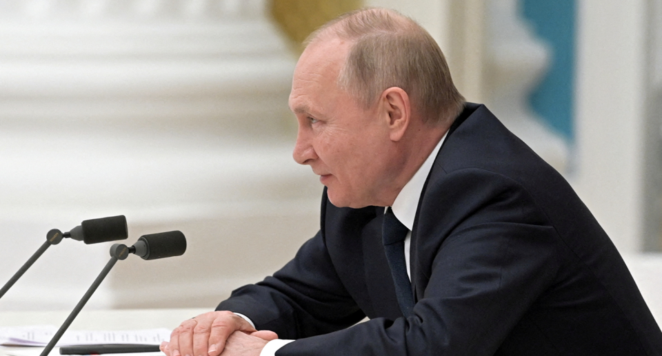 President Vladimir Putin in front of two microphones.