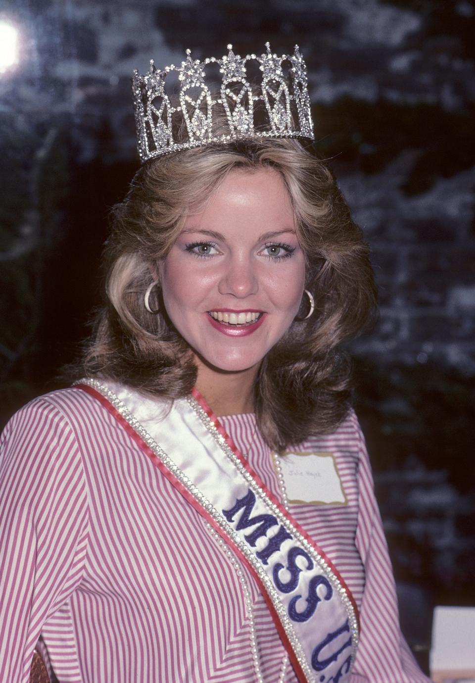 Miss USA 1983 Julie Hayek smiles while wearing a pageant and a tiara.