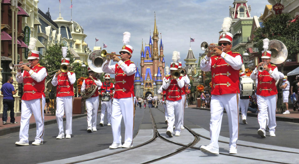 The Main Street Philharmonic marching band performs in the Magic Kingdom at Walt Disney World, in Lake Buena Vista, Fla., Wednesday, Sept. 30, 2020. The Walt Disney Co. announced Tuesday that it is planning to lay off 28,000 workers in its theme parks division in California and Florida. The company has been squeezed by limits on attendance at its parks and other restrictions due to the pandemic. (Joe Burbank/Orlando Sentinel via AP)