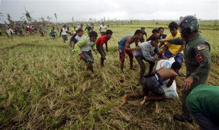 A Philippine Air Force personnel officer (R) tries to push away survivors of Super Typhoon Haiyan from the moving rotor of a helicopter, as its crew deploys aid into a remote area some 25km (17 miles) west of Tacloban cityNovember 17, 2013. The Philippine and U.S. Air Forces are flying rice, clothes and drinking water into remote areas of the central Philippines, which are unreachable by vehicles. REUTERS/Wolfgang Rattay