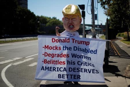 Protestor Tom Moran wears a paper mache head of Republican U.S. presidential nominee Donald Trump as he demonstrates outside Hofstra University, the site of the September 26 first presidential debate between Trump and Democratic presidential nominee Hillary Clinton, in Hempstead, New York, U.S., September 25, 2016, REUTERS/Brian Snyder