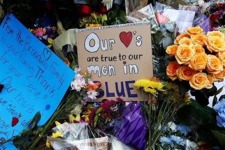 A "Our hearts are true to the men in blue" sign is pictured at a makeshift memorial at police headquarters following the multiple police shootings in Dallas, Texas, U.S., July 10, 2016. REUTERS/Carlo Allegri