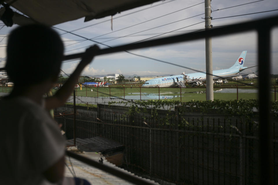 A boy looks at a damaged Korean Air plane after it overshot the runway at the Mactan-Cebu International Airport in Cebu, central Philippines early Monday Oct. 24, 2022. The Korean Air plane overshot the runway while landing in bad weather in the central Philippines late Sunday, but authorities said all 173 people on board were safe. (AP Photo/Juan Carlo De Vela)