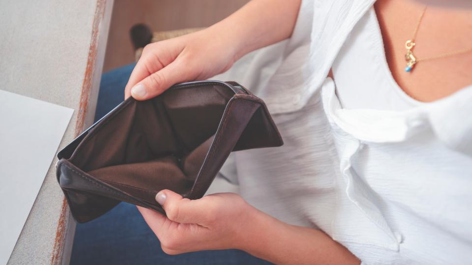 A woman opening an empty wallet.