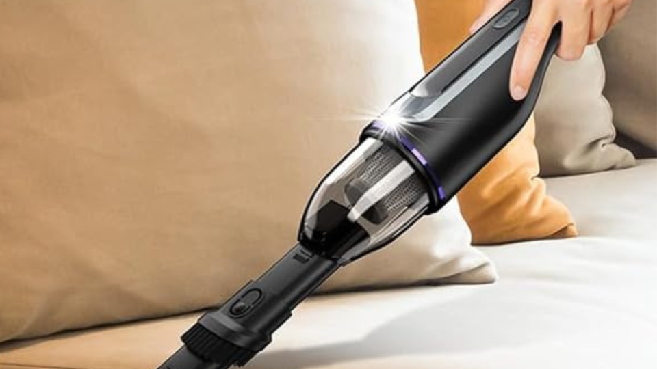 Someone using the Drecell handheld vacuum to clean a couch
