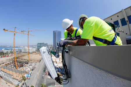 FILE PHOTO: Telecommunications workers Chris Viens and Guy Glover install a new 5G antenna system for AT&T's 5G wireless network in downtown San Diego, California, U.S., April 23, 2019. REUTERS/Mike Blake/File Photo