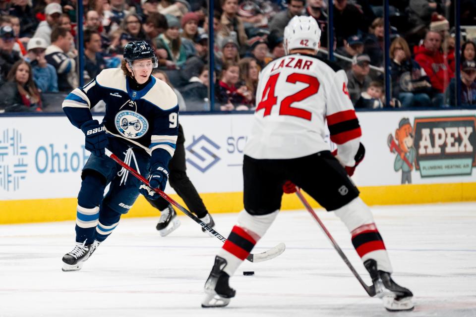 Dec 16, 2023; Columbus, Ohio, USA;
Columbus Blue Jackets center Kent Johnson (91) looks for an open pass around New Jersey Devils center Curtis Lazar (42) during the third period of their game on Saturday, Dec. 16, 2023 at Nationwide Arena.