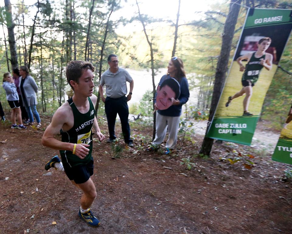 Marshfield's Gabe Zullo runs past his banner during the first lap of their meet against Hingham at Marshfield High on Wednesday, Oct. 12, 2022. He would place third overall. Marshfield girls would win 19-39 while Marshfield boys won 19-44.