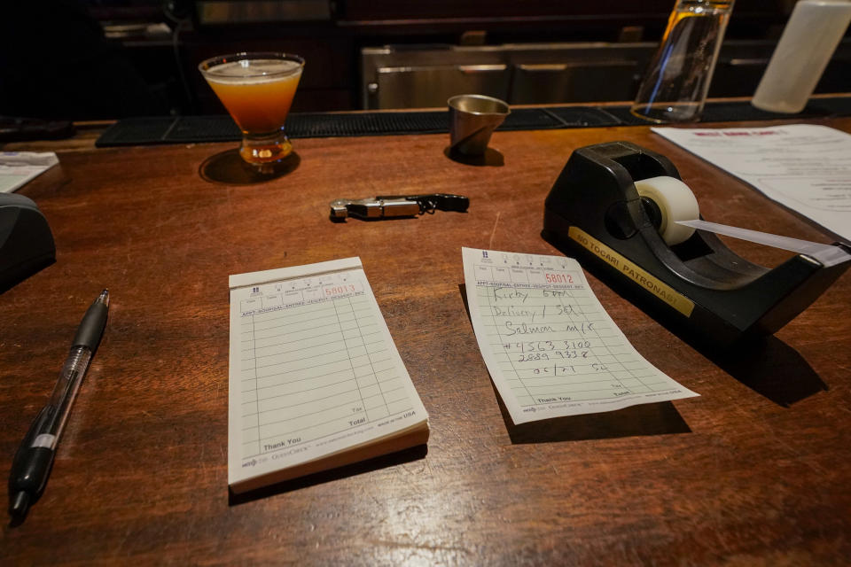 A to-go order is seen on the bar of the West Bank Café, Saturday, Jan. 9, 2021, in the Hell's Kitchen neighborhood of New York. The boarded-up windows and For Rent signs are all over the place in Manhattan’s Hell’s Kitchen neighborhood. Nearby, the Broadway theaters are all dark. But the economic darkness brought on by the coronavirus pandemic has had a few bright spots. A couple of well-loved venues have gotten financial boosts, thanks to online fundraising campaigns and even a telethon. (AP Photo/Mary Altaffer)