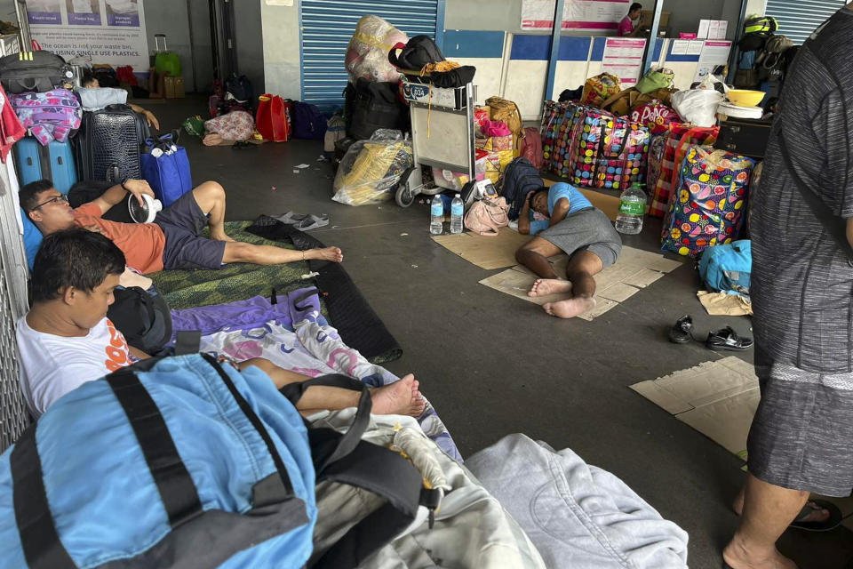 In this photo provided by the Philippine Coast Guard, stranded passengers stay at passenger terminal after sea travel was suspended due to Typhoon Doksuri in Manila, Philippines on Tuesday July 25, 2023. The powerful typhoon blew closer to the northern Philippines on Tuesday, forcing thousands of evacuations and a halt to sea travel ahead of torrential rains and tidal surges up to 3 meters (nearly 10 feet). (Philippine Coast Guard via AP)