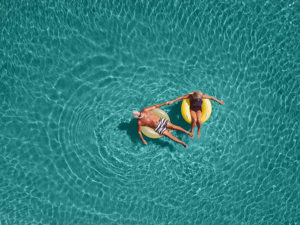 Two seniors float in a pool.