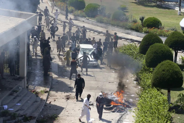 Supporters of Pakistan's former Prime Minister Imran Khan damage a car inside the compound of Radio Pakistan as they protest against the arrest of their leader, in Peshawar, Pakistan, Wednesday, May 10, 2023. Imran Khan appeared in court Wednesday, a day after he was dragged from another court and arrested in Islamabad, setting off clashes between his supporters and police. Angry protesters stormed and set fire to a building housing Radio Pakistan in the northwest as the death toll from the violence rose to four. (AP Photo/Muhammad Sajjad)