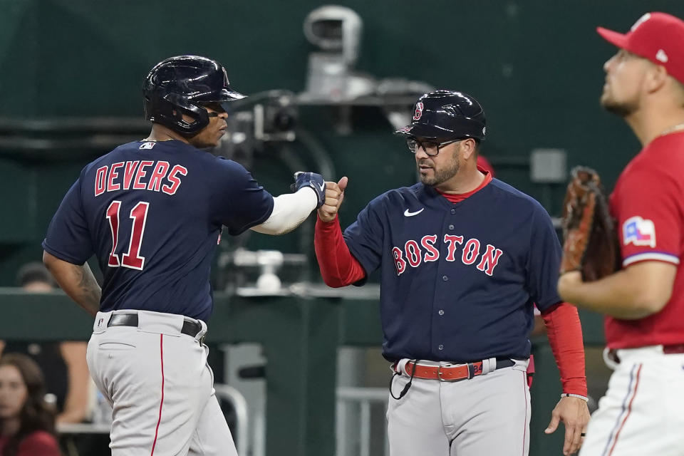 Boston Red Sox's Rafael Devers (11) gets a fist bump from first base coach Ramon Vazquez after hitting an RBI single against the Texas Rangers during the third inning of a baseball game in Arlington, Texas, Friday, May 13, 2022. (AP Photo/LM Otero)