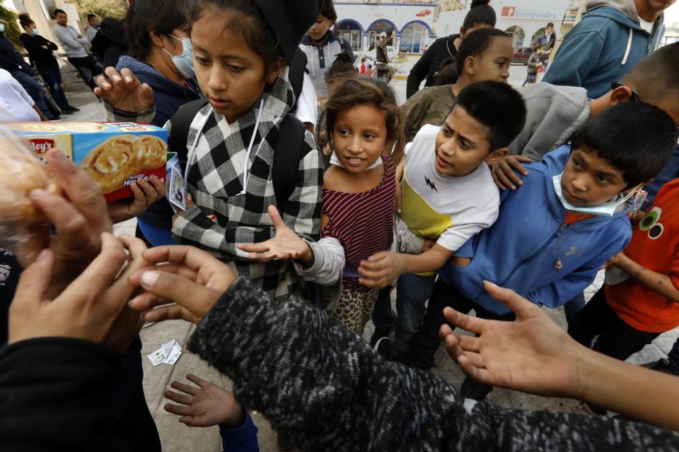 Children reach out for a pastry.